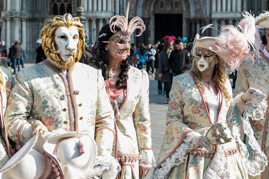 Fotos von kostümierten Faschingssbesucher beim Karneval von Venedig auf dem Markusplatz, Venezia, Italien. Im Hintergrund der Markusdom.